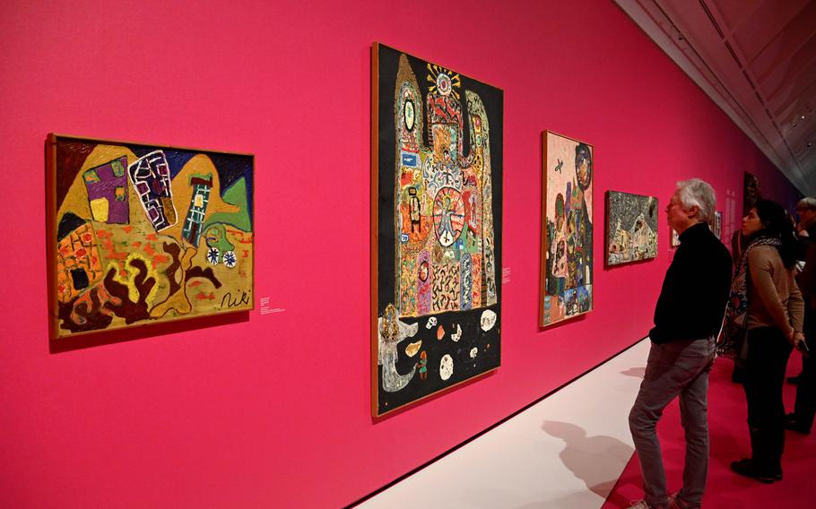 Visitors look at “The Castle of the Monster and the Bride (or The Sunken Wedding),” at the Niki de Saint Phalle exhibit at the Schirn in Frankfurt, Germany. In the foreground is her “Play with Me.”