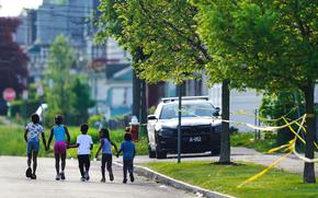 Children walk hand-in-hand near the scene of a shooting at a supermarket in Buffalo, N.Y., May 15, 2022. The shooting rampage at a Buffalo supermarket, carried out by an 18-year-old who was flagged for making a threatening comment at his high school the year before, highlights concerns over whether schools are adequately supporting and screening students.