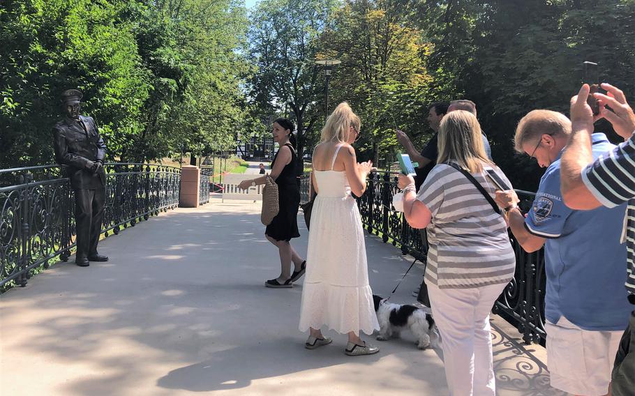 People wait on a bridge in Bad Nauheim, Germany, to take pictures next to a statue of Elvis Presley, Aug. 15, 2021. The spa town holds a festival in August in memory of Presley, who lived in Bad Nauheim when he served in the U.S. Army from 1958-1960.