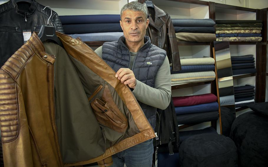 Cumali Palta, a tailor outside Incirlik Air Base in Turkey, shows off a leather jacket with a pistol holster that he hopes will appeal to the U.S. airmen deployed at the nearby base on Feb. 24, 2023.