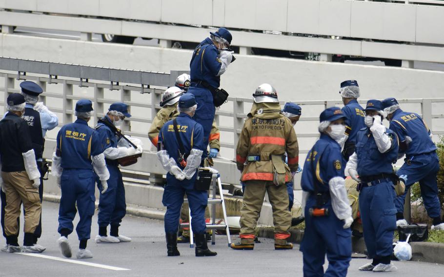 Police and firefighters inspect the scene where a man is reported to set himself on fire, near the Prime Minister's Office in Tokyo, Wednesday, Sept. 21, 2022. The man was taken to a hospital, in an apparent protest against a planned state funeral next week for the assassinated former leader Shinzo Abe, officials and media reports said.