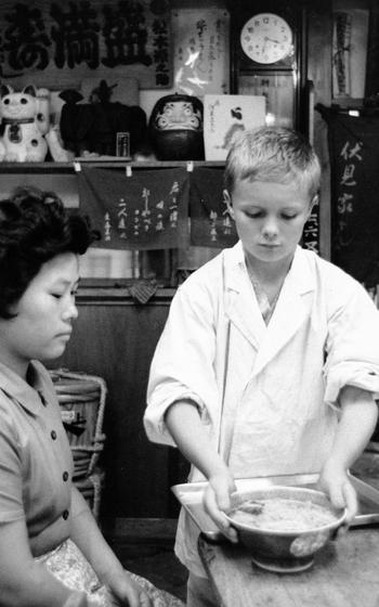 A child serves a bowl of Soba noodles