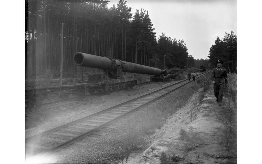 The 90-foot long tube of the German railway gun is waiting to be turned into scrap metal. The massive Nazi Germany-produced railway gun was being disassembled in the woods near Grafenwöhr. Although nicknamed “Big Bertha” by the American forces, the gun — one of the two 800mm K(E) railway guns developed and produced by the German steel and armament producer Krupp in the early 1940s — was either called “Gustav” or “Dora” by the Germans. 