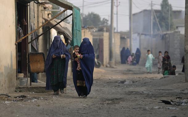 Burqa-clad Afghan women walk on a street in a a neighbourhood with a mostly Afghan population in Karachi, Pakistan, Friday, Jan. 26, 2024.