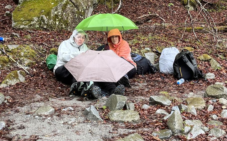 Hikers from Yokosuka Naval Base, Japan, keep an injured Japanese man warm with an emergency blanket and umbrellas near Mount Hinokiboramaru in Kanagawa prefecture, April 15, 2023.