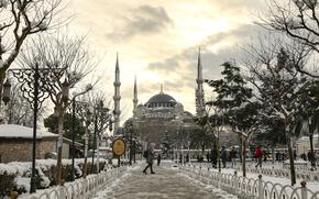 People walk in a snow-covered park with the iconic Haghia Sophia in the background at Istanbul, Tuesday, Jan. 25, 2022. Rescue crews in Istanbul and Athens on Tuesday cleared roads that had come to a standstill after a massive cold front and snowstorms hit much of Turkey and Greece, leaving countless people and vehicles in both cities stranded overnight in freezing conditions. (AP Photo/Emrah Gurel)