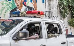 A police convoy drives past a wall painted with the president's image down the alley of the entrance to the residence of the president in Port-au-Prince on July 15, 2021, in the wake of Haitian President Jovenel Moise's assassination on July 7, 2021. (Valerie Baeriswyl/AFP via Getty Images/TNS)