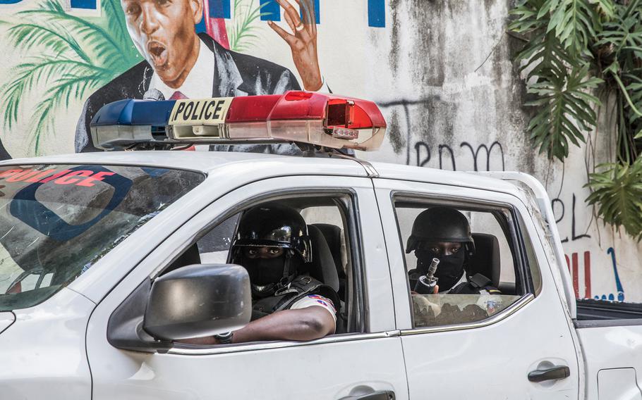 A police convoy drives past a wall painted with the president’s image down the alley of the entrance to the residence of the president in Port-au-Prince on July 15, 2021, in the wake of Haitian President Jovenel Moise’s assassination on July 7, 2021.