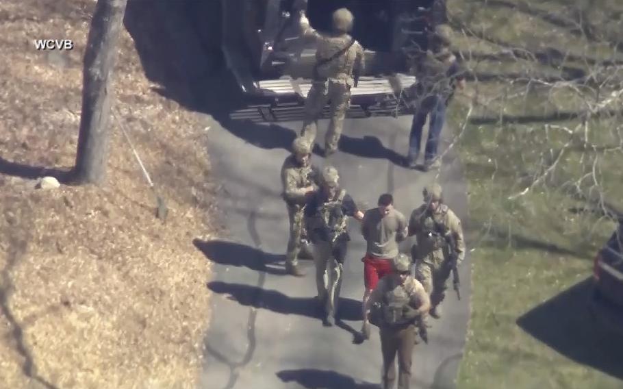 This image made from video provided by WCVB-TV, shows Jack Teixeira, in T-shirt and shorts, being taken into custody by armed tactical agents on Thursday, April 13, 2023, in Dighton, Mass. 