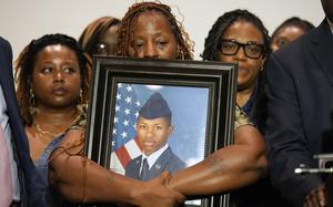 Senior Airman Roger Fortson’s family holding a picture of him.