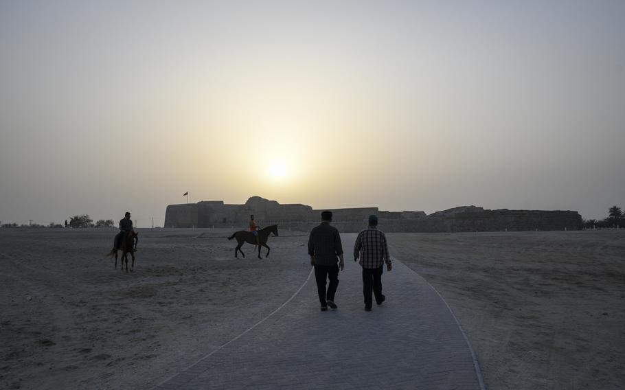 Equestrian riders pass visitors to the Qal’at al-Bahrain, on April 16, 2022. The history-rich fort is a UNESCO world heritage site in the Bahraini capital, Manama.