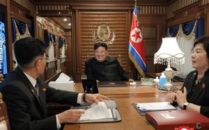 North Korean leader Kim Jong Un sits at the head of a wooden table on a train.