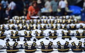 FILE - The new hats and shoulder bars for the graduates sit on a table before the start of the U.S. Coast Guard Academy's 141st Commencement Exercises, May 18, 2022, in New London, Conn. A U.S. Coast Guard Academy cadet who was expelled for becoming a father will get his degree as part of a legal settlement, his attorneys said Thursday, Oct. 6, 2022. (AP Photo/Stephen Dunn, File)