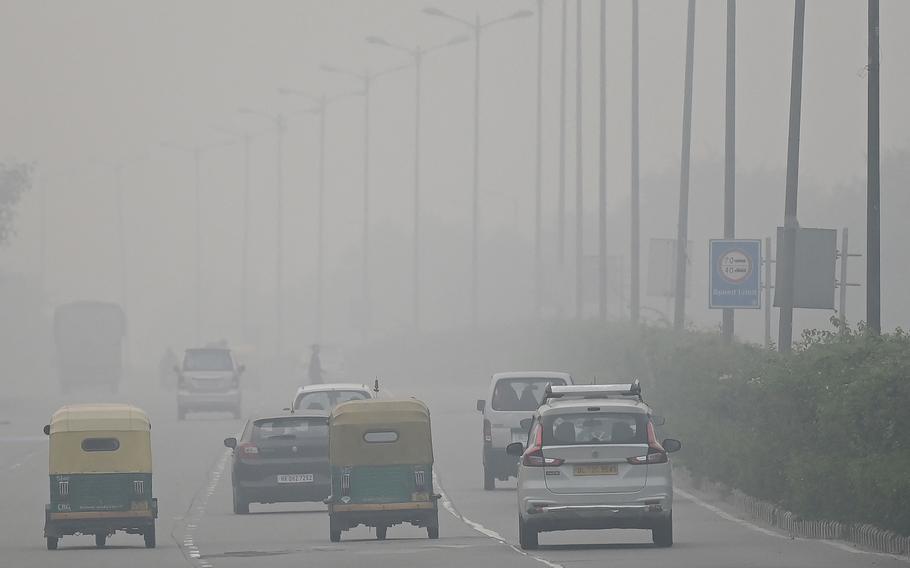 Commuters make their way along a road amid smoggy conditions in New Delhi, India on Sunday, Nov. 7, 2021. 