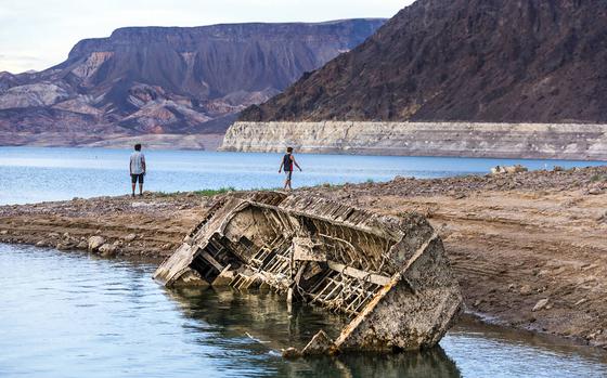 Hikers pass a previously sunken World War II-era Higgins landing craft that once was 185 feet below the surface and is now nearly on the shoreline as waters keep receding on July 26, near Boulder City, Nev.