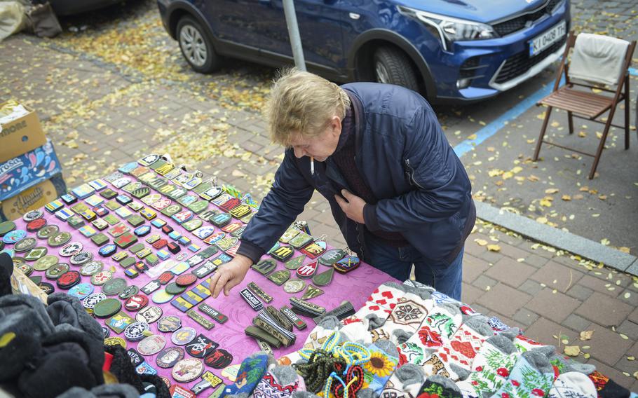 Sergiy Zhornavoy, a long-time street vendor in Kyiv, Ukraine, rearranges morale and unit patches at his cart as he waits for customers during a dreary afternoon on Oct. 27, 2022. Russia’s invasion of Ukraine in 2022 chased away the carefree tourists who once bought keychains and other trinkets, and Zhornavoy said only a few vendors are left selling their wares.