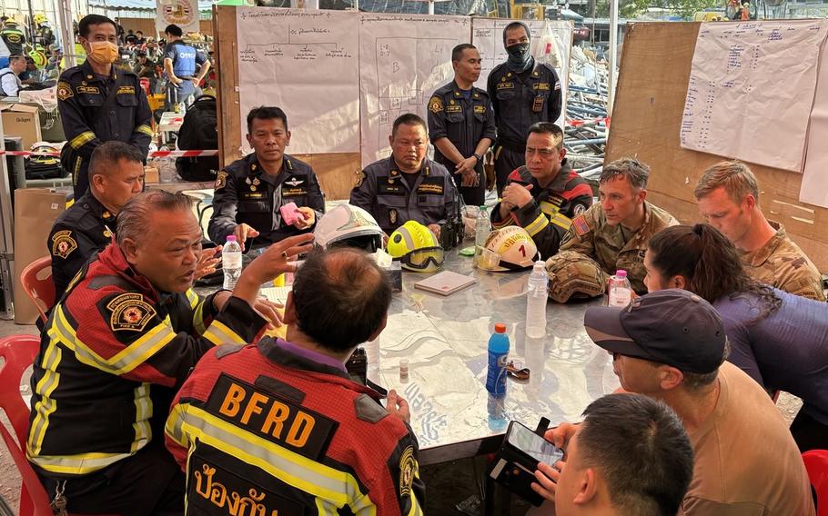 U.S. military personnel sit at a table with first responders at a search and rescue center in Bangkok.