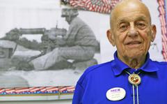 Retired Sgt. Maj. Marion P. Carcirieri, manager at the Marine Mart aboard Camp Geiger, stands in front of a photograph of himself during the Vietnam War in the Marine Mart staff office, Aug. 5. Carcirieri fought at the Battle of Okinawa, in the Korean War and in the Vietnam War during his 31 year Marine Corps career. Carcirieri's brother also fought at the Battle of Okinawa on the other side of the island. "It was a really memorable experience for me."