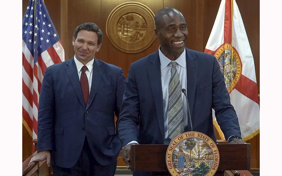 Dr. Joseph Ladapo smiles on Sept. 21, 2021, after being appointed surgeon general of Florida by Gov. Ron DeSantis, seen at left in the background.