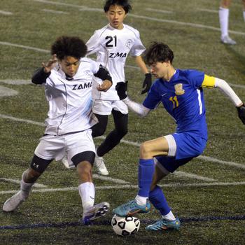 Zama‘s Jayden Parker and Yokota’s Senna Solberg scuffle for the ball during Friday’s DODEA-Japan boys soccer season opener at Yokota’s Fred Bonk Memorial Field. The Trojans won 1-0, their first victory over the Panthers in four years.