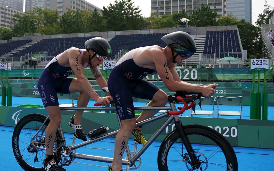 Team USA’s Bradley Snyder, left, and Greg Billington ride a tandem bike on their way to Paralympic triathlon gold at Odaiba Marine Park in Tokyo, Saturday, Aug. 28, 2021. Snyder is a Navy veteran who lost his sight from a blast in Afghanistan in 2011. 