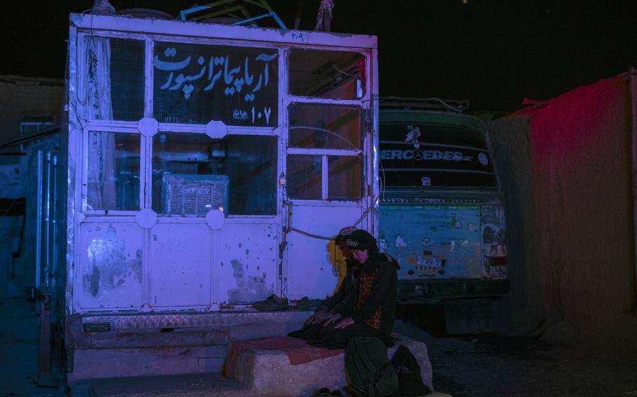 Two Afghan men pray at a bus station in Herat, Afghanistan, on Tuesday, Nov. 23, 2021, before they embark on a bus for a 300-mile trip south to Nimrooz near the Iranian border. 