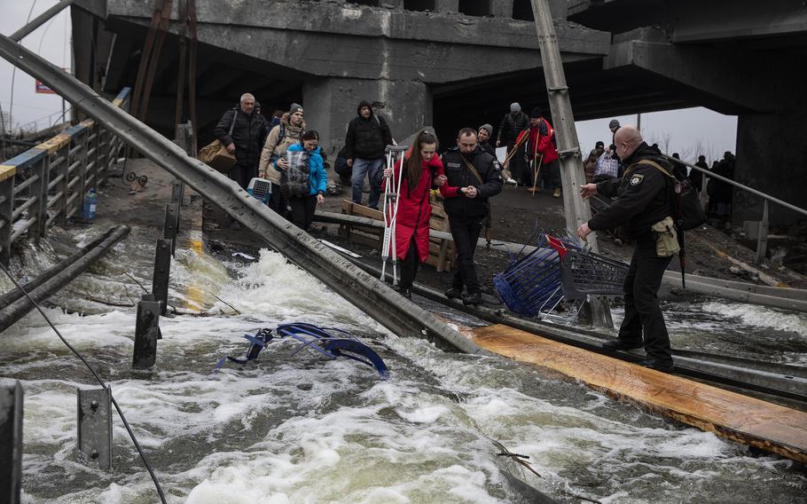 Ukrainians flee the area of Irpin at a damaged bridge on the outskirts of Kyiv, Ukraine, on Monday, March 7, 2022. 