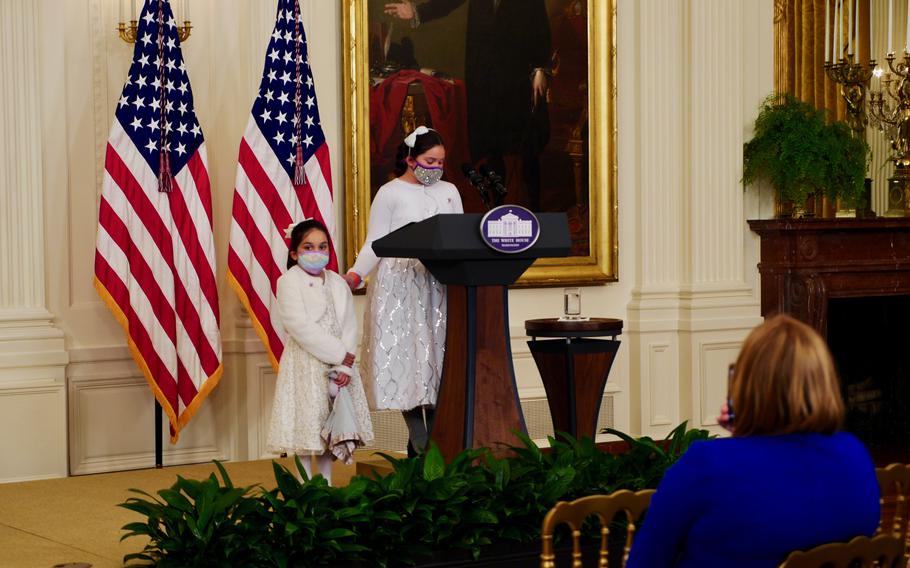 Gabby Rodriguez, 9, touches her six-year-old sister Ava’s shoulder as she speaks about their experiences as children of a wounded veteran at an event honoring child caregivers in the White House’s East room on Wednesday, Nov. 10, 2021. 