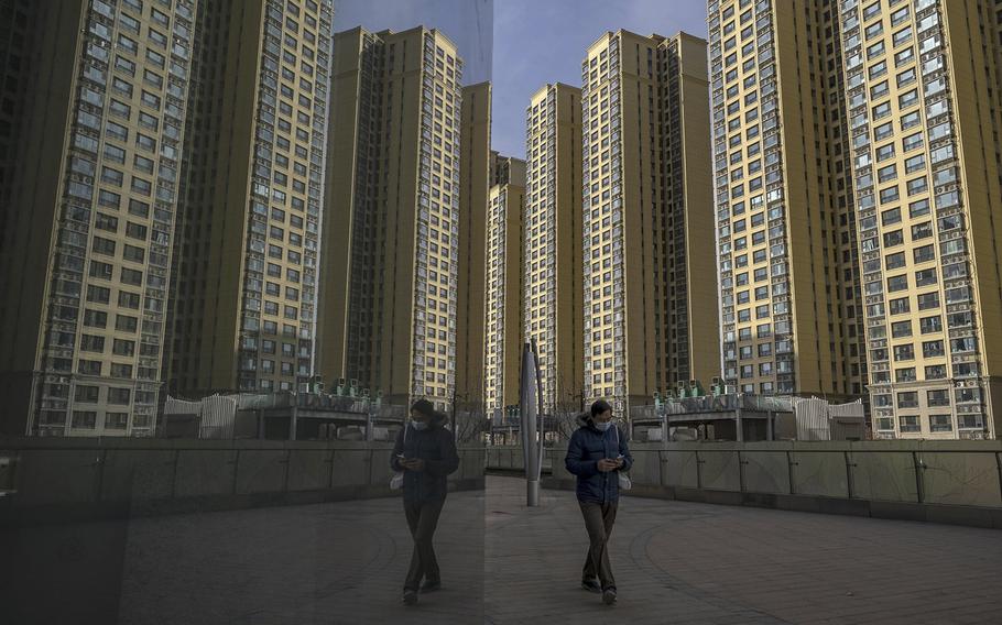 A pedestrian walks past apartment buildings at China Evergrande Group’s City Plaza development in Beijing, China, on Dec. 10, 2021. 