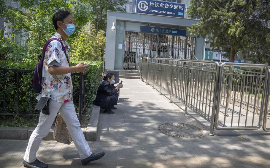 A man wearing a face mask walks past the closed exit of a subway station in Beijing, Wednesday, May 4, 2022. Beijing on Wednesday closed around 10% of the stations in its vast subway system as an additional measure against the spread of the coronavirus.