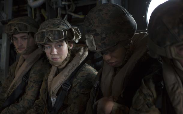 A Marine wearing a helmet looks at her team.