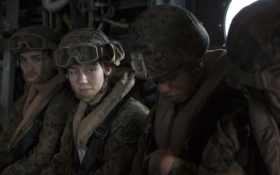 A Marine wearing a helmet looks at her team.