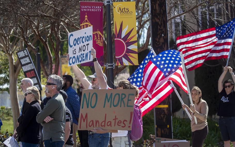 Protesters hold signs at an anti-vaccine protest on March 9, 2022, next to Santa Clara University in Santa Clara, California. The event was in response to two students suing Santa Clara University over its COVID-19 vaccine booster shot requirement. 
