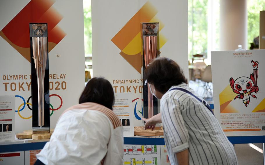 People check out torches for the Tokyo Olympic and Paralymic games on display at Chigasaki City Hall in Kanagawa prefecture, Japan, Tuesday, June 8, 2021. 