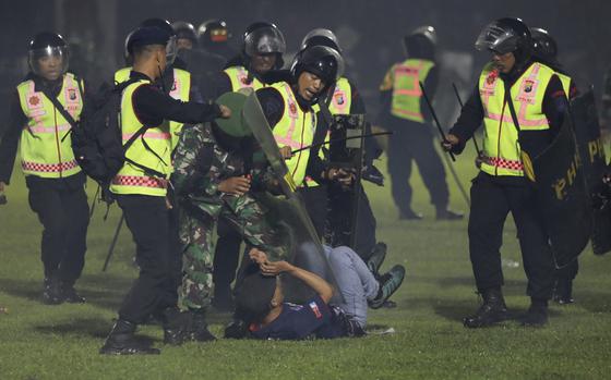 Security officers detain a fan during a clash between supporters of two Indonesian soccer teams at Kanjuruhan Stadium in Malang, East Java, Indonesia, Saturday, Oct. 1, 2022. Panic following police actions left over 100 dead, mostly trampled to death, police said Sunday. 