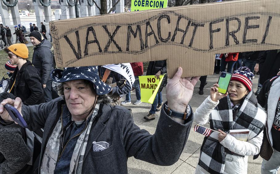 Participants in a rally in opposition to vaccine mandates, including a man with a poster referencing the sign over the gate at the Auschwitz concentration camp, march to the Lincoln Memorial in Washington, D.C., Jan. 23, 2022.
