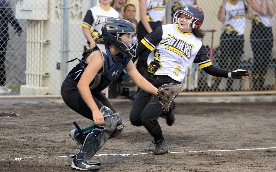 Kadena's Nao Grove slides toward home plate safely as Kubasaki catcher Taylor Tobin awaits the throw during Tuesday's Okinawa softball game. The Panthers won 5-3.