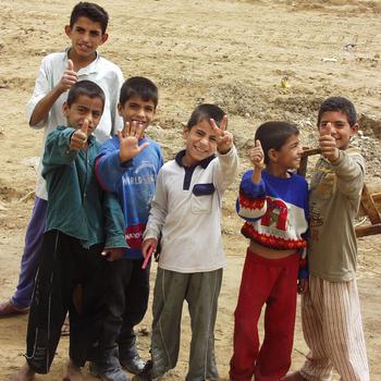 Children smile and make signs to the camera.