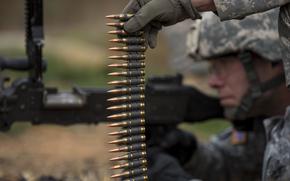 A U.S. soldier holds up a belt of 7.62 mm rounds during an M240B machine gun qualification range at Camp Atterbury, Ind., in 2015. There was a decline in annual global arms revenue in 2022, according to a new report by the Stockholm International Peace Research Institute. Preliminary data suggests an upswing for weapons contractors in 2023.