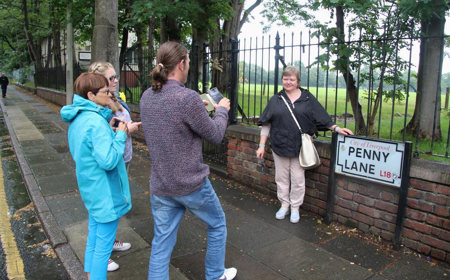 Tourists photograph each other in front of the street sign of Penny Lane in 2019. All four Beatles grew up in Mossley Hill, a suburb of England’s Liverpool, and their song “Penny Lane” is full of local references.