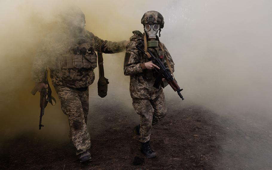 Ukrainian soldiers walk through dust and smoke