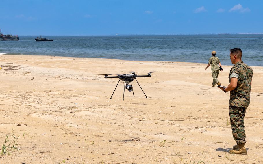 A Marine on a beach pilots a drone.