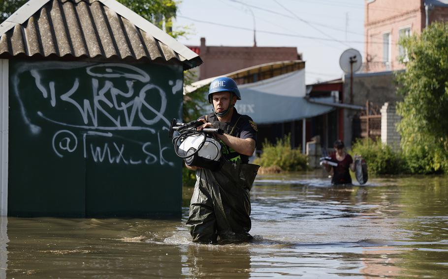 A rescuer helps to save belongings of locals from flooding following the destruction of the Kakhovka dam on June 7, 2023, in Kherson, Ukraine.