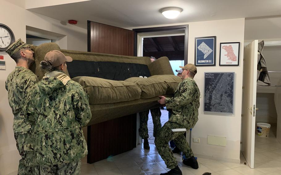 Naval Air Station Sigonella personnel move a waterlogged sofa out of a home in the base's Marinai housing complex, Oct. 29, 2021. With floodwaters gone, residents and base officials are beginning clean up and the recovery process. 