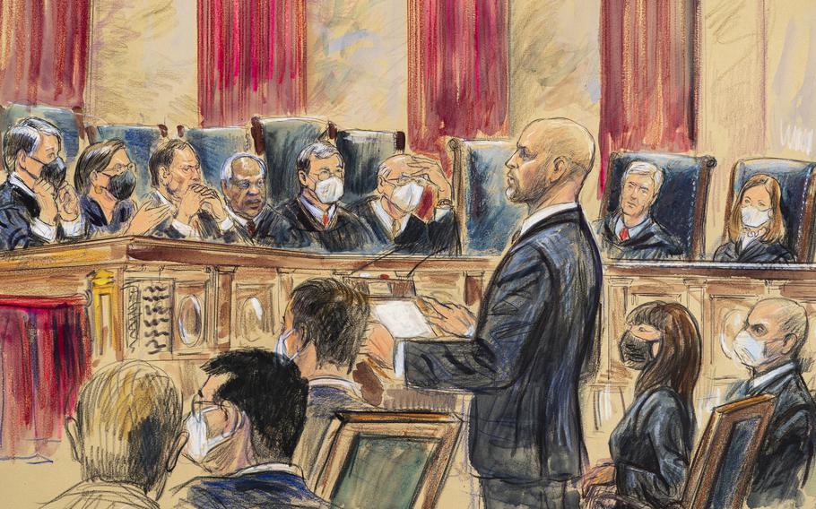 A courtroom sketch depicts lawyer Scott Keller standing at the Supreme Court in Washington on Friday, Jan. 7, 2022, as he argued on behalf of more than two dozen business groups seeking an immediate order from the Supreme Court to halt a Biden administration order to impose a vaccine-or-testing requirement on the nation’s large employers during the COVID-19 pandemic. Solicitor General Elizabeth Prelogar, the Biden administration’s top Supreme Court lawyer, is seated at right.