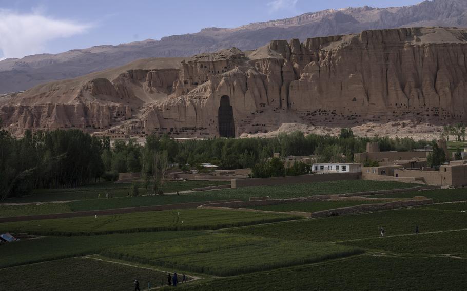 Villagers walk in the fields near the niche of a giant Buddha statue in Afghanistan.