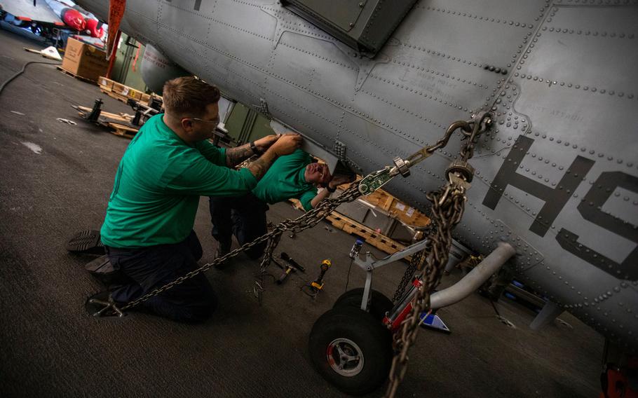 Crew members work on a helicopter in the hangar bay aboard the USS Gerald R. Ford on Thursday, Oct. 6, 2022.
