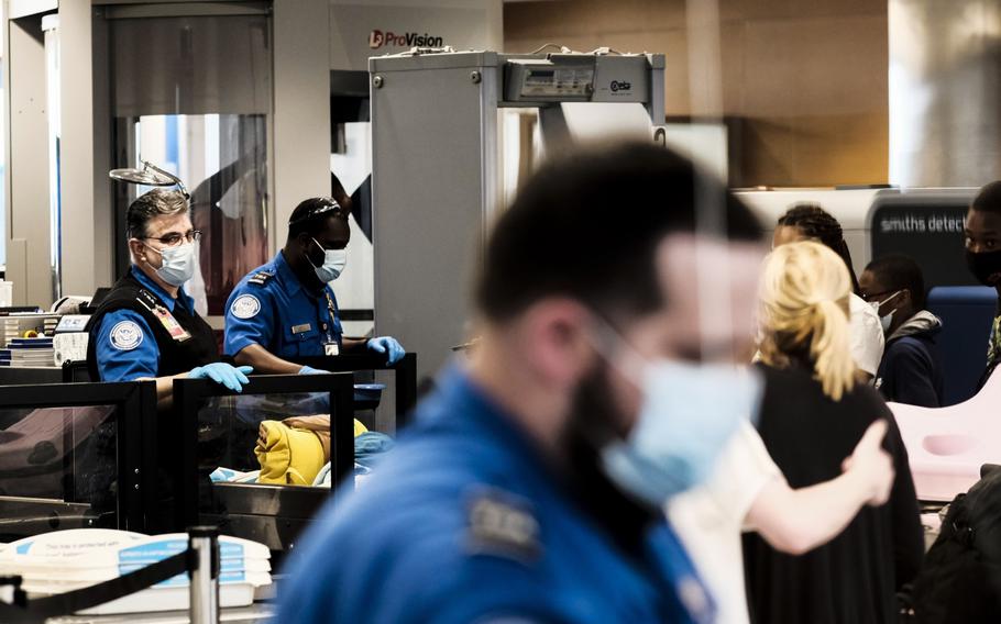 A Transportation Security Administration agent screens travelers and their luggage at a checkpoint in the Detroit Metropolitan Wayne County Airport in Romulus, Mich., on June 12, 2021. 