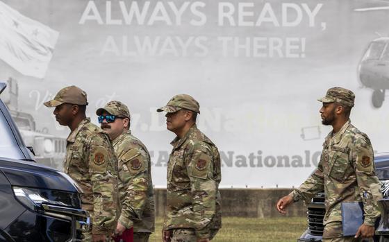 Troops in uniform walk in front of a sign that says Always Ready Always There.