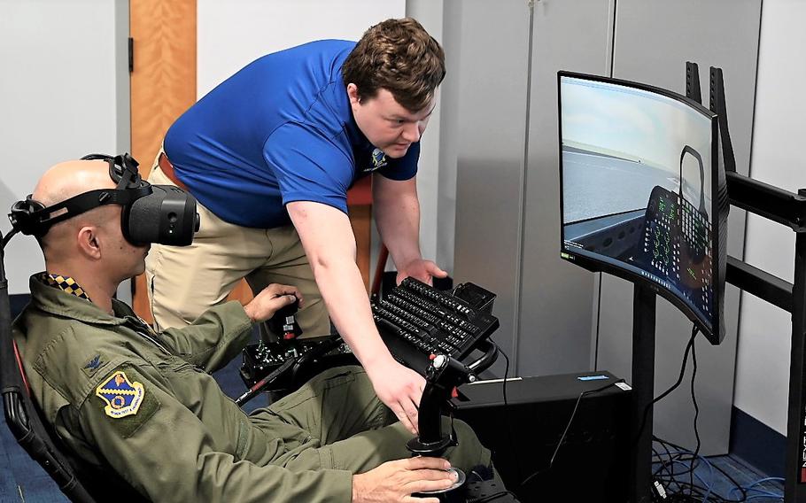 Matt Murdock, a Simulators Division contractor, assists Col. Cameron Dadgar, Nevada Test and Training Range commander, during a demonstration of a virtual reality flight simulator in the new Sims Holodeck.